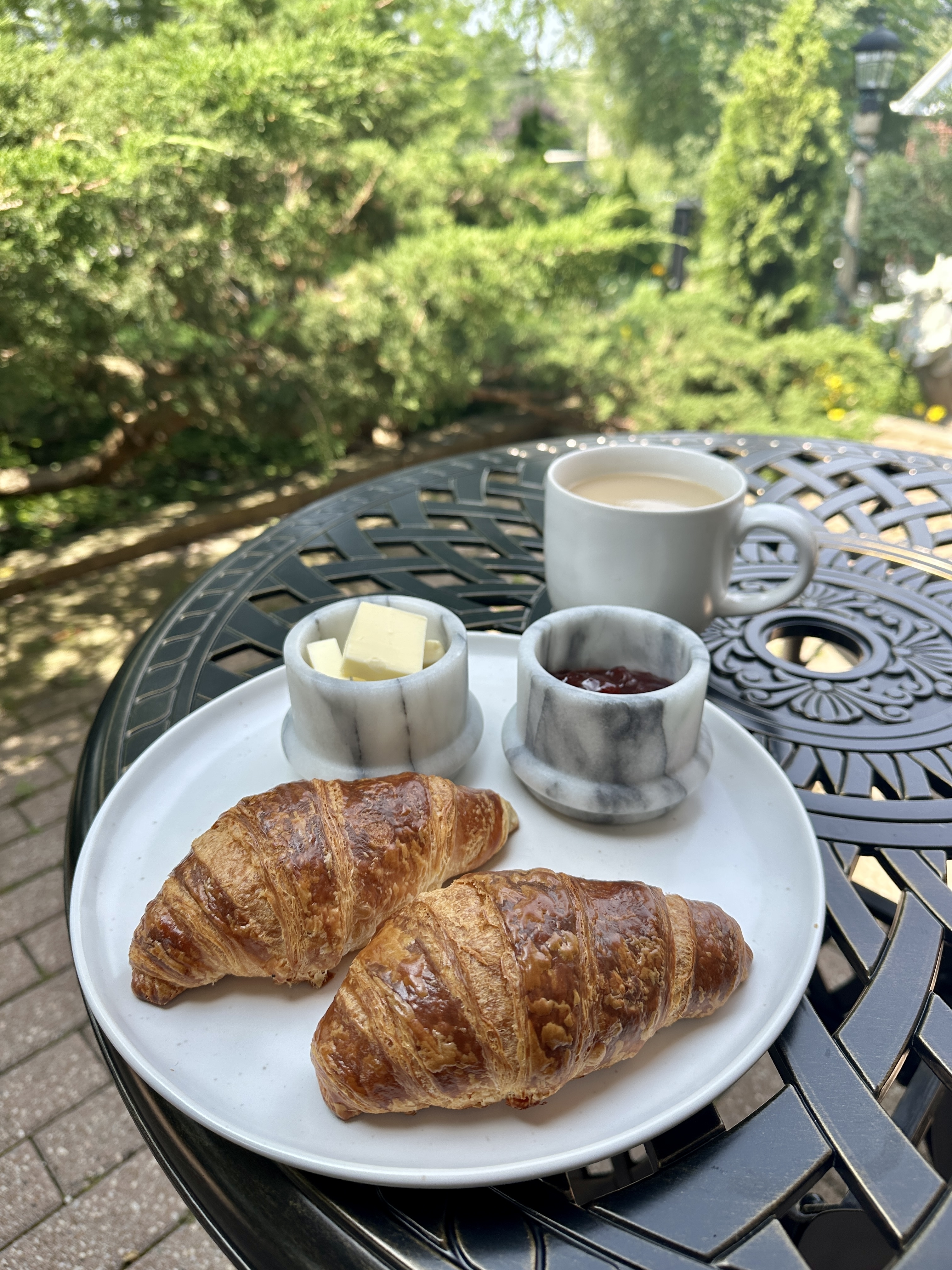 Croissants, jam, and coffee on a table outdoors.