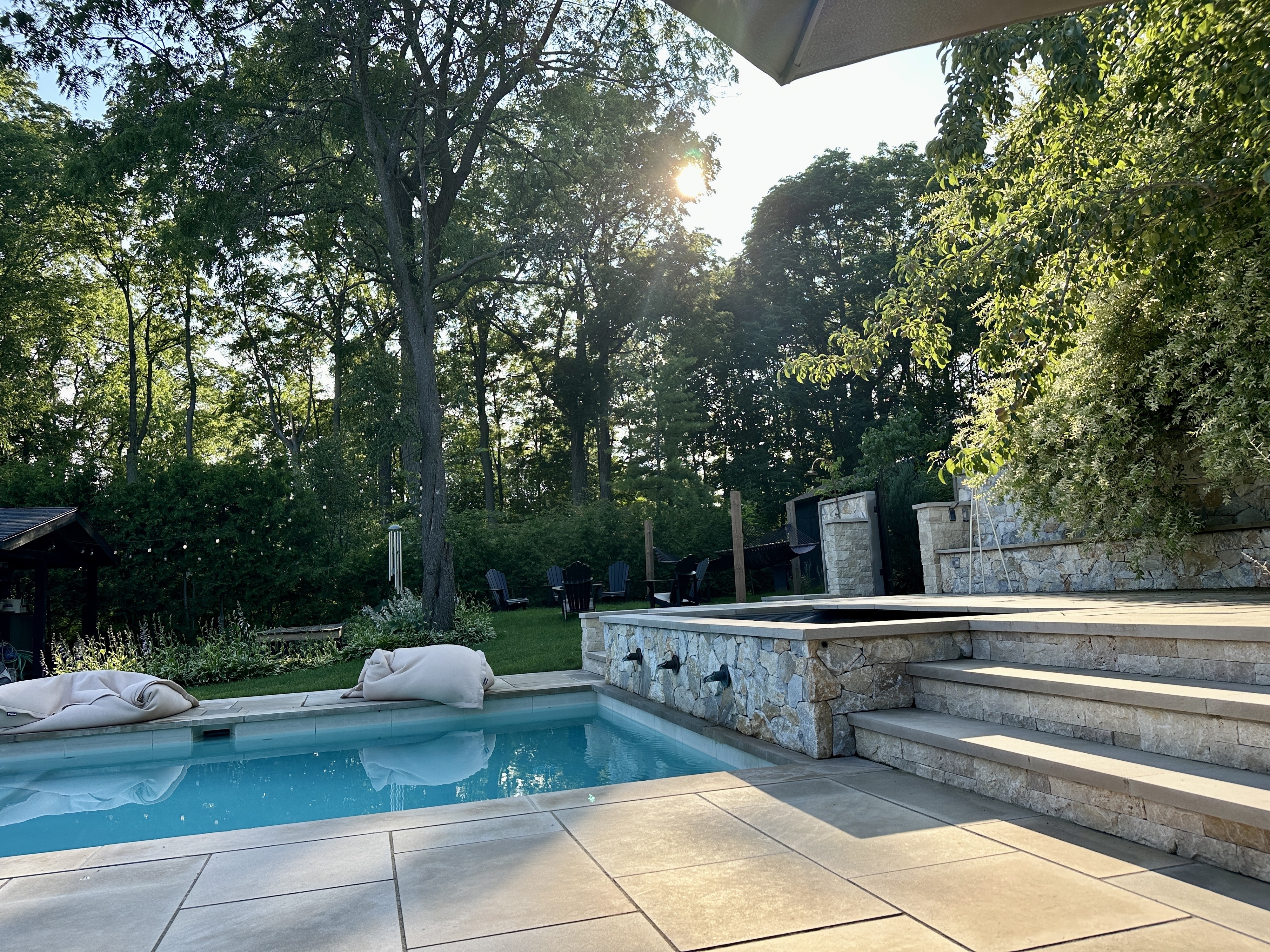 A pool and deck with the sun shining through