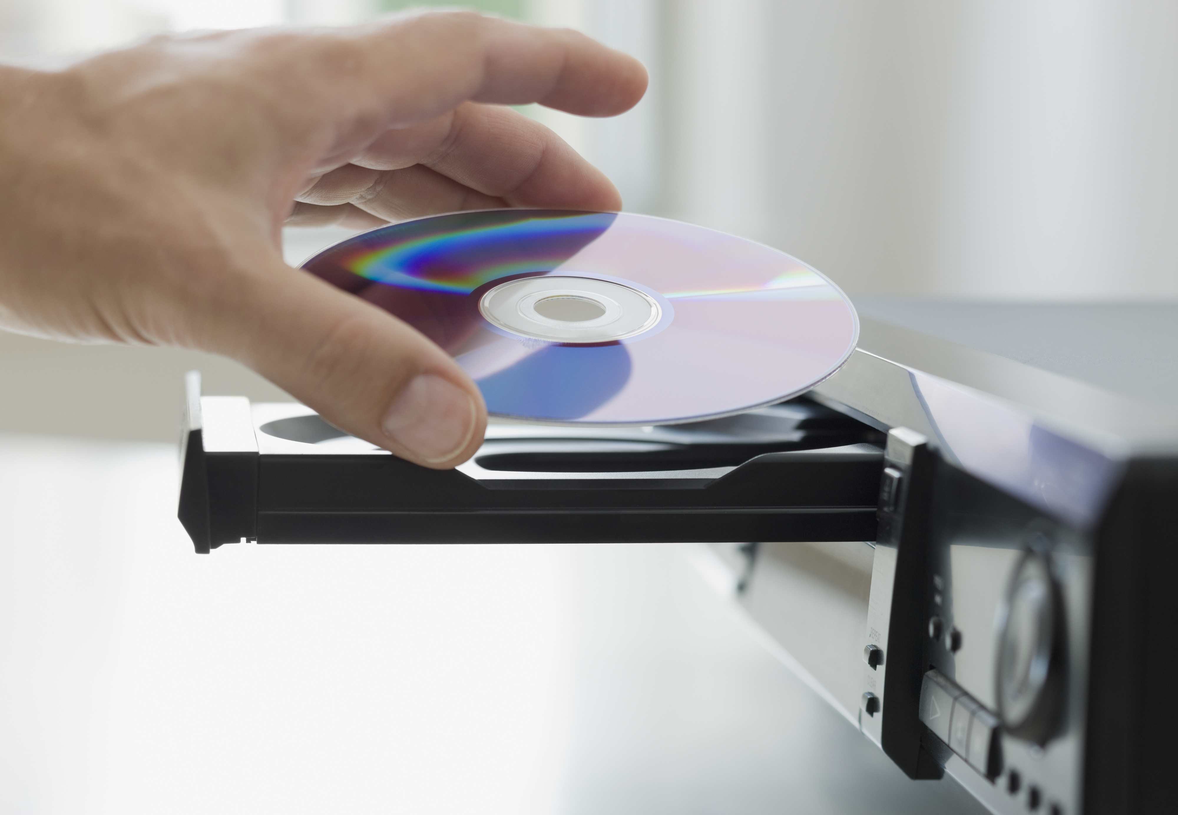 A hand putting a CD into a CD player