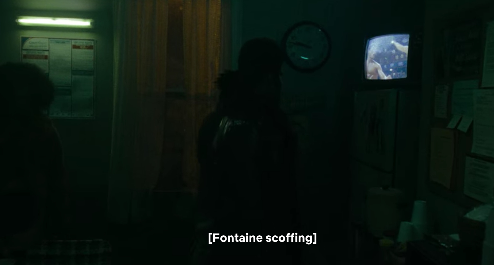 A dark room with a television on showing a movie