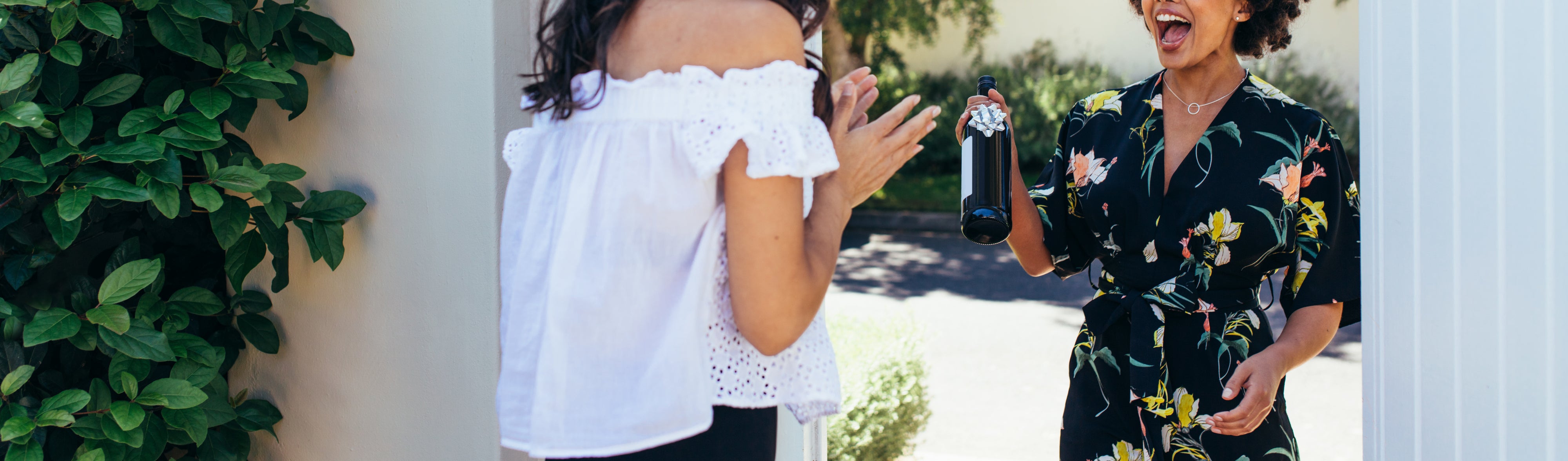 Woman giving a wine bottle her friends at entrance door