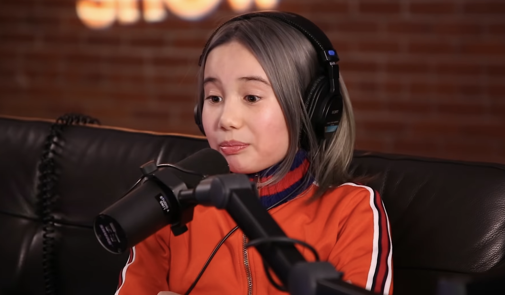 Close-up of Tay seated at a microphone