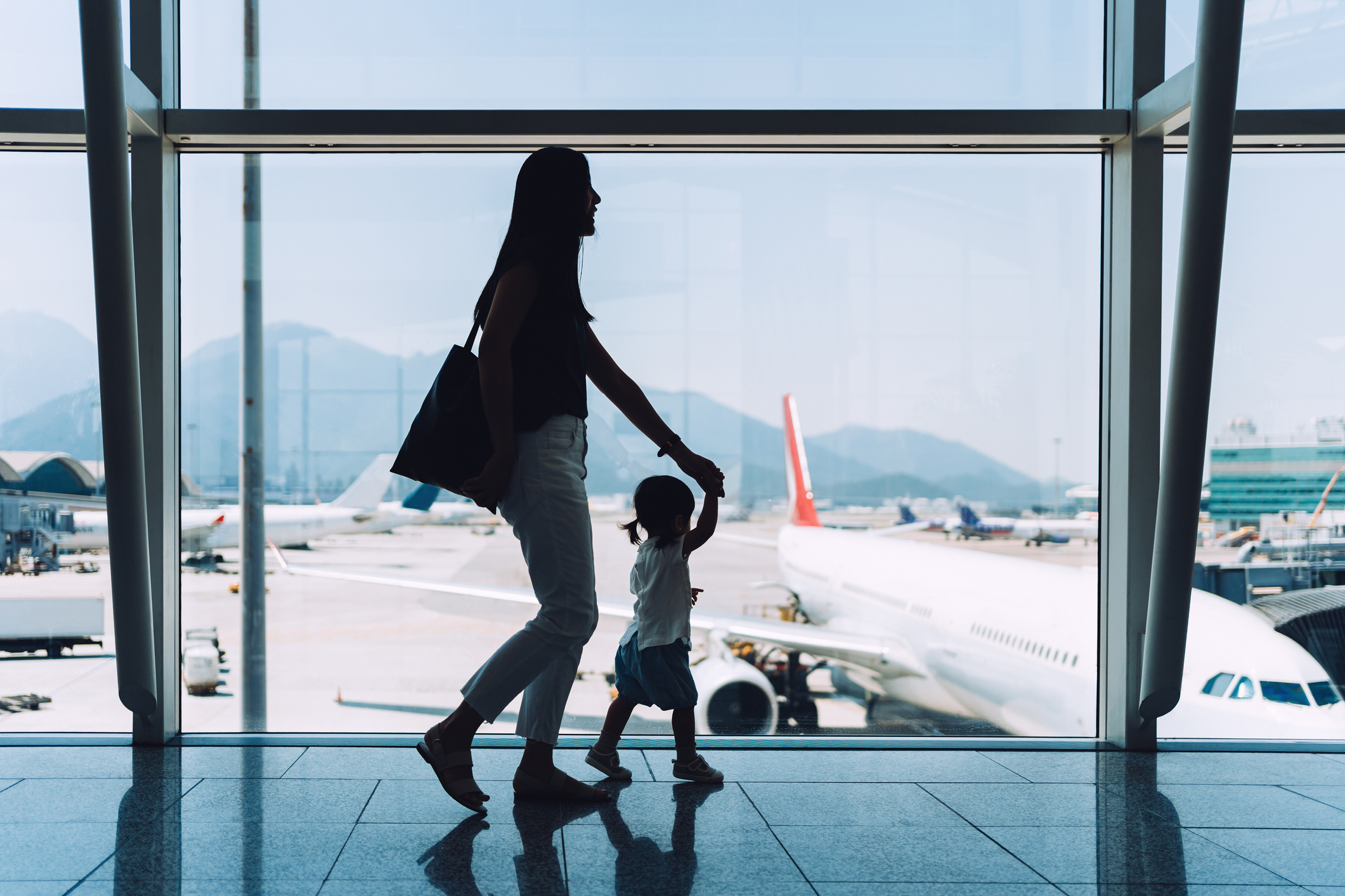 A mother and her daughter are walking through an airport