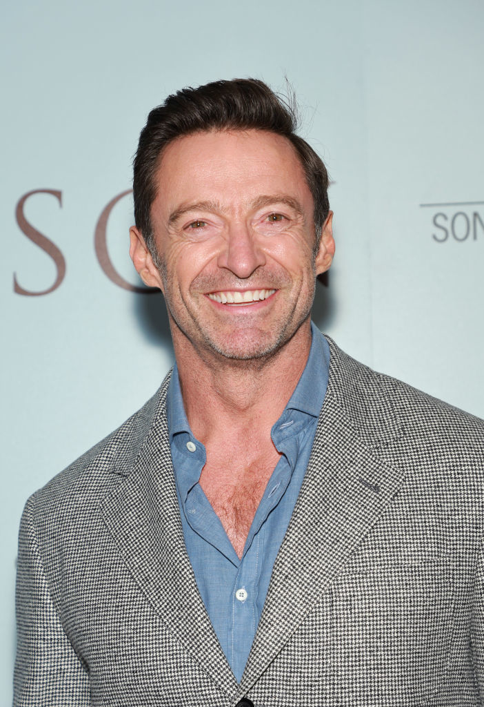 Close-up of Hugh smiling in a suit at a media event