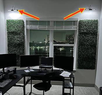 The lights above faux ivy decor on the wall of a home office