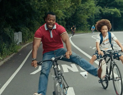 A man and his son riding their bikes down the street