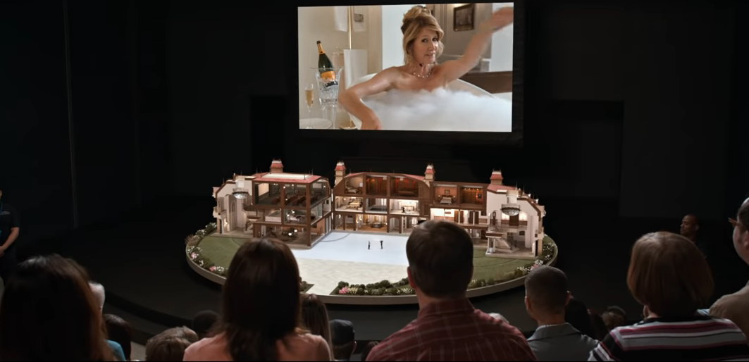 People in an audience watching the screen showing a woman taking a bubble bath