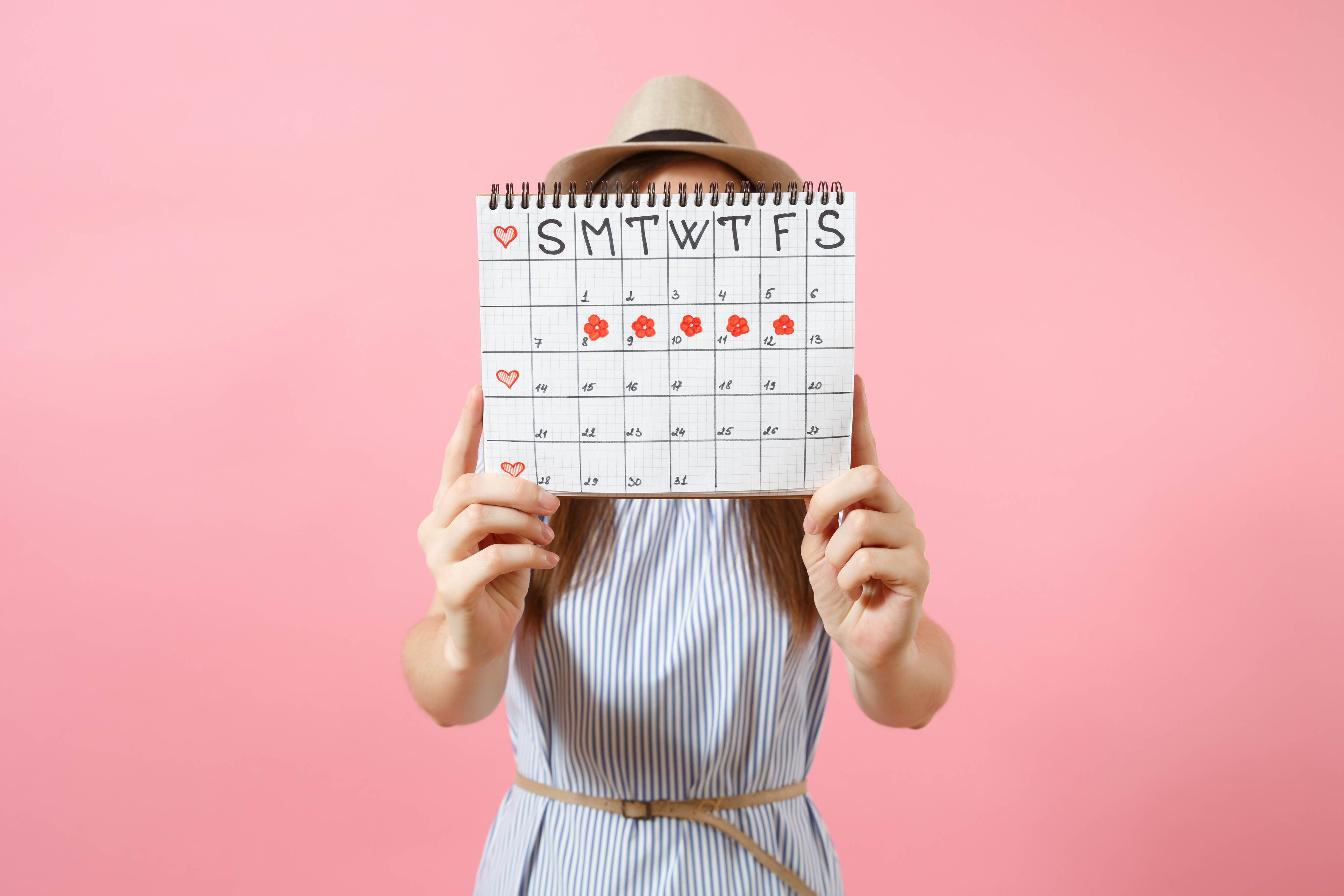 woman holding a calendar with the five days of her period marked with red flowers