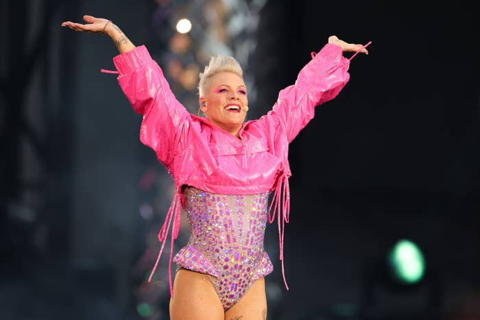 pink with her arms above her head on stage