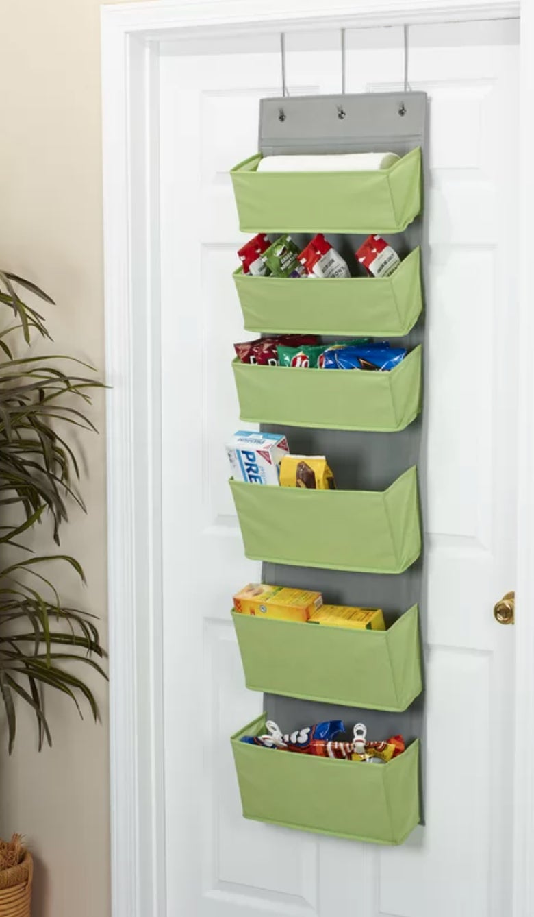 a green over-the-door organizer with six pockets filled with snacks
