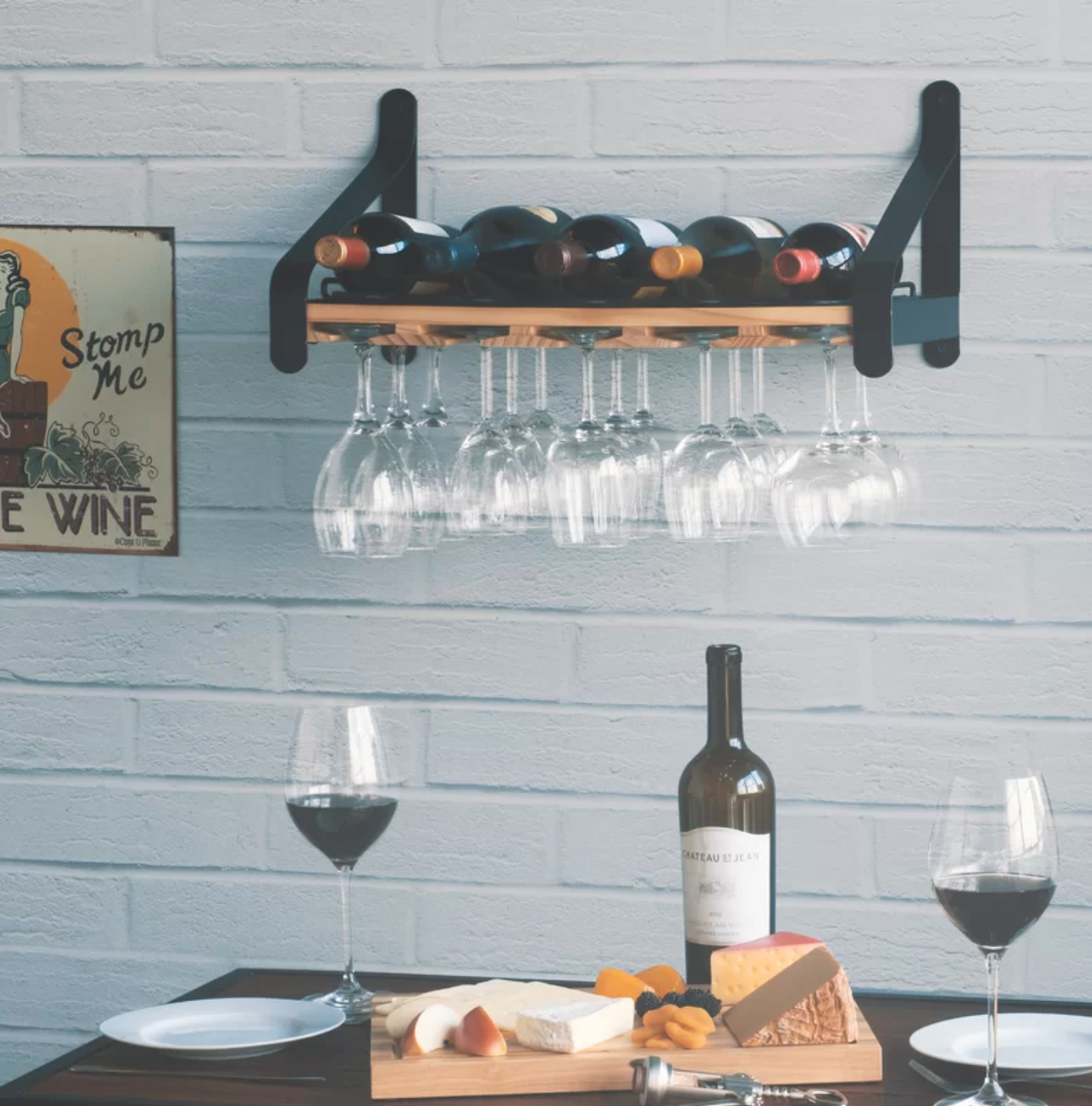 a hanging wine rack filled with bottles and glasses, mounted on a white brick wall