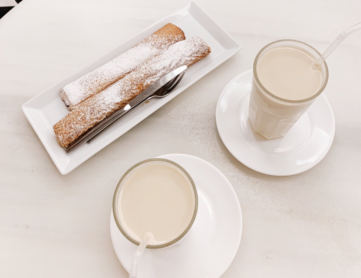 Two glasses of horchata are being served with fartón cake