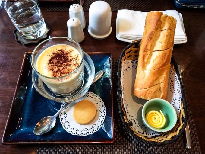 A cup of egg coffee is being served with a baguette