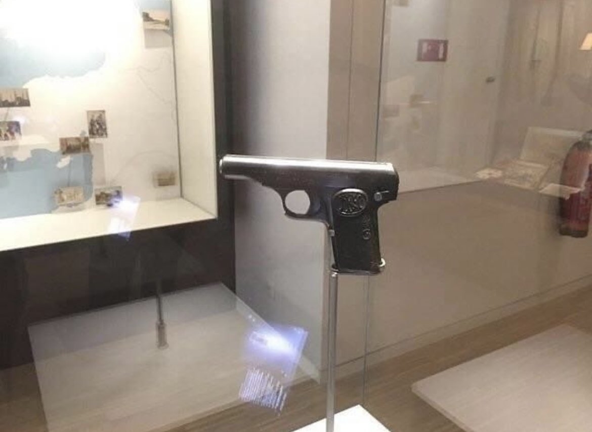 A silver pistol behind glass
