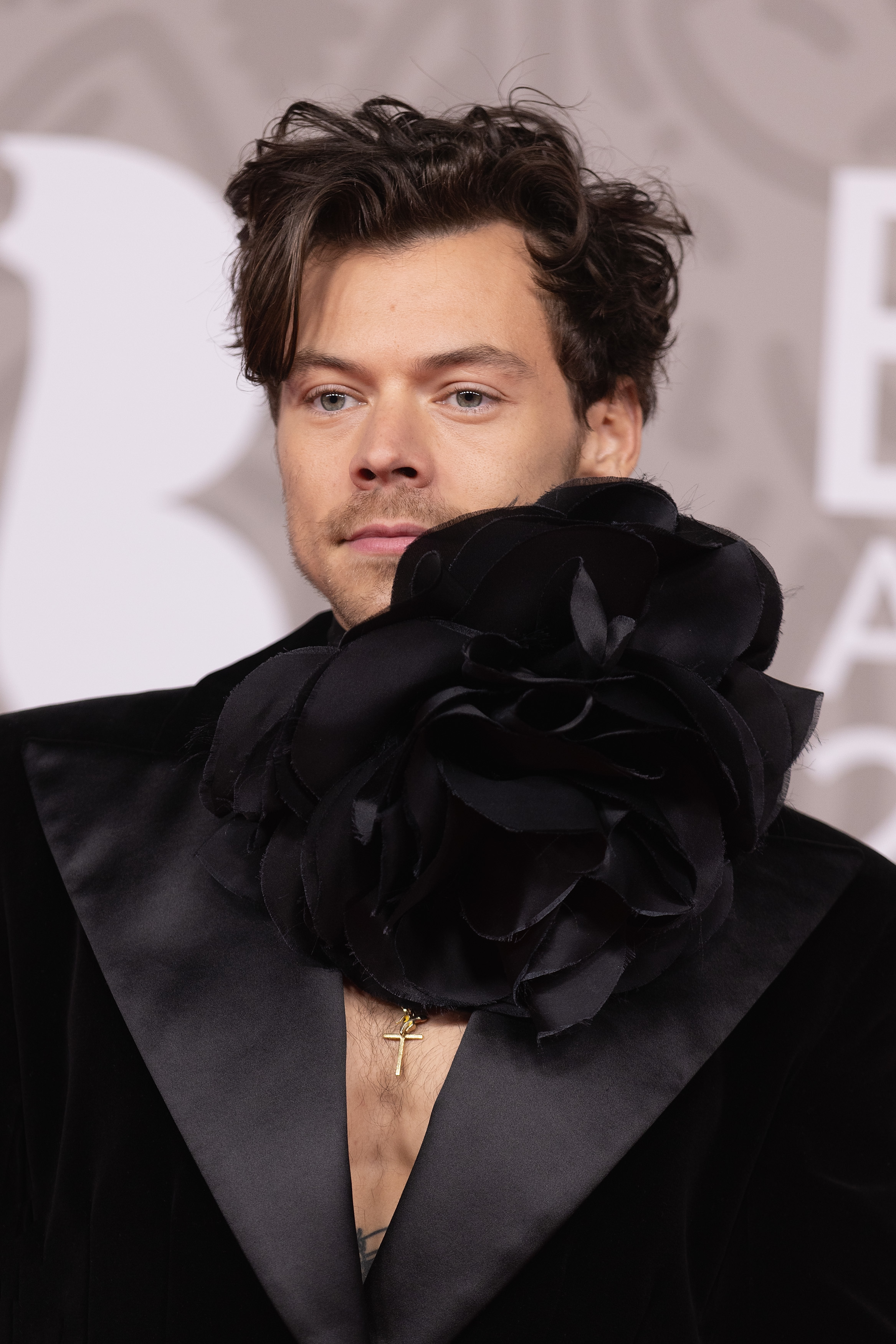 Closeup of Harry Styles in a suit with a massive flower attached to the shoulder