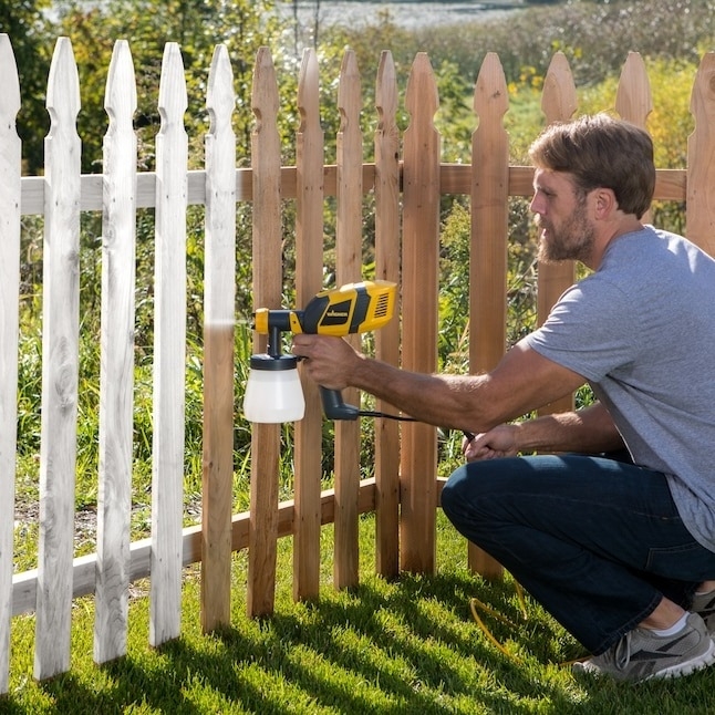 model using the handheld sprayer to paint a fence