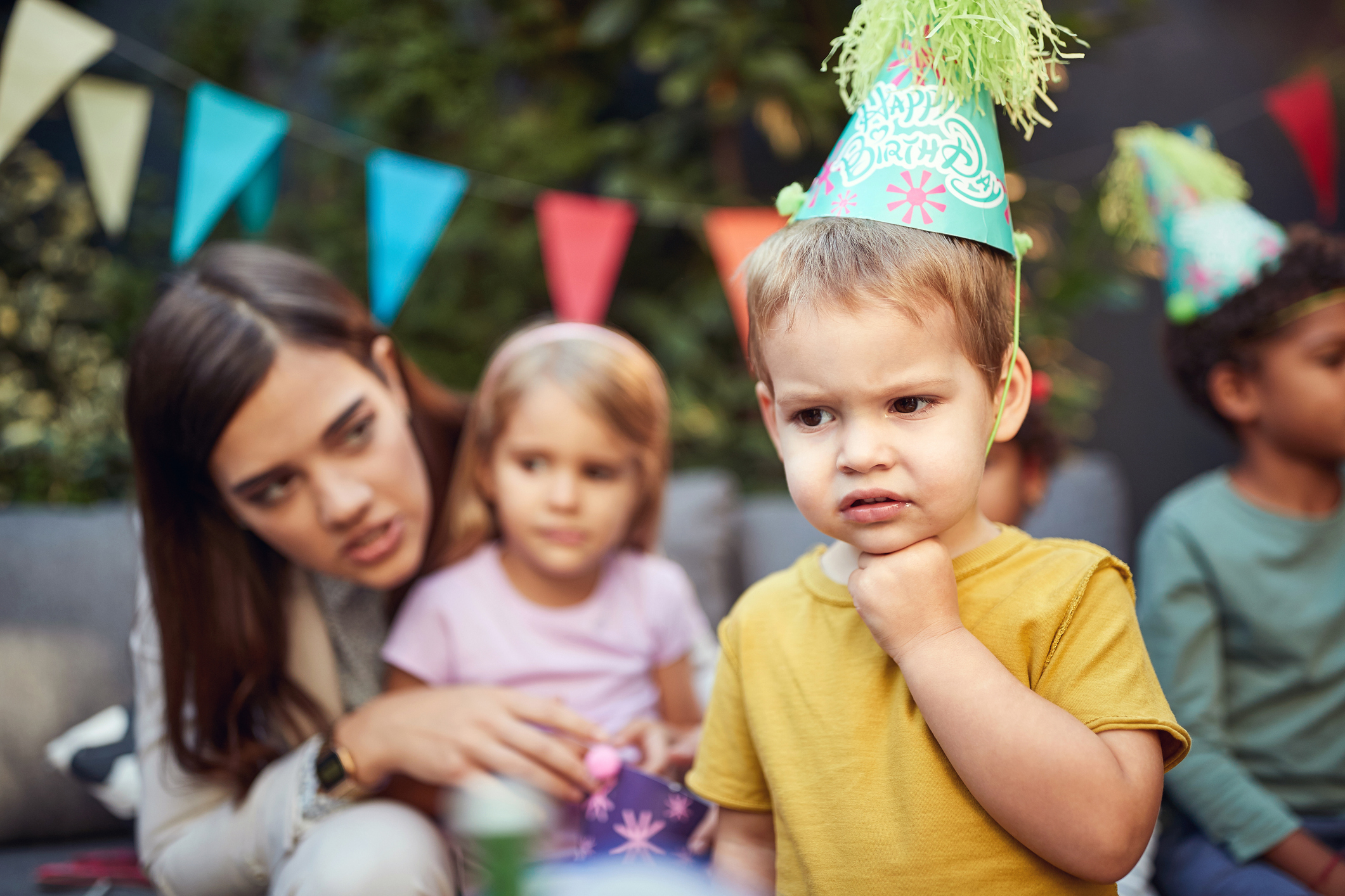 A young kid looking unhappy at a birthday party