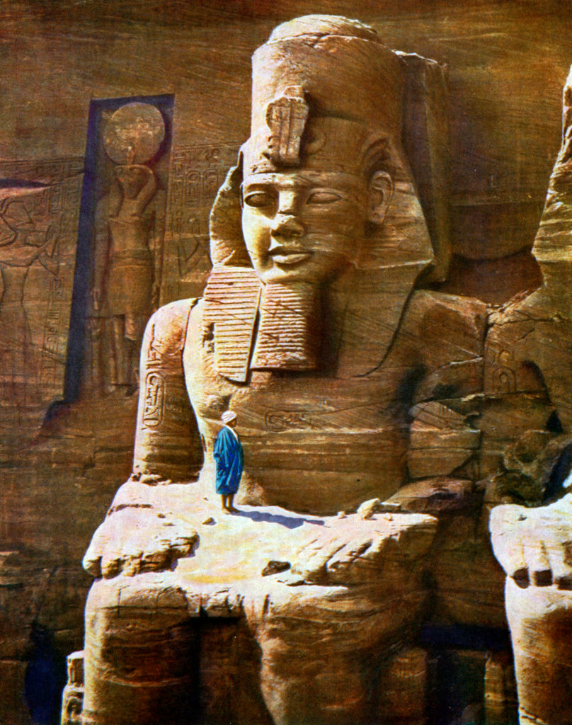 A person in a robe stands in the &quot;lap&quot; of the enormous statue emerging from rock