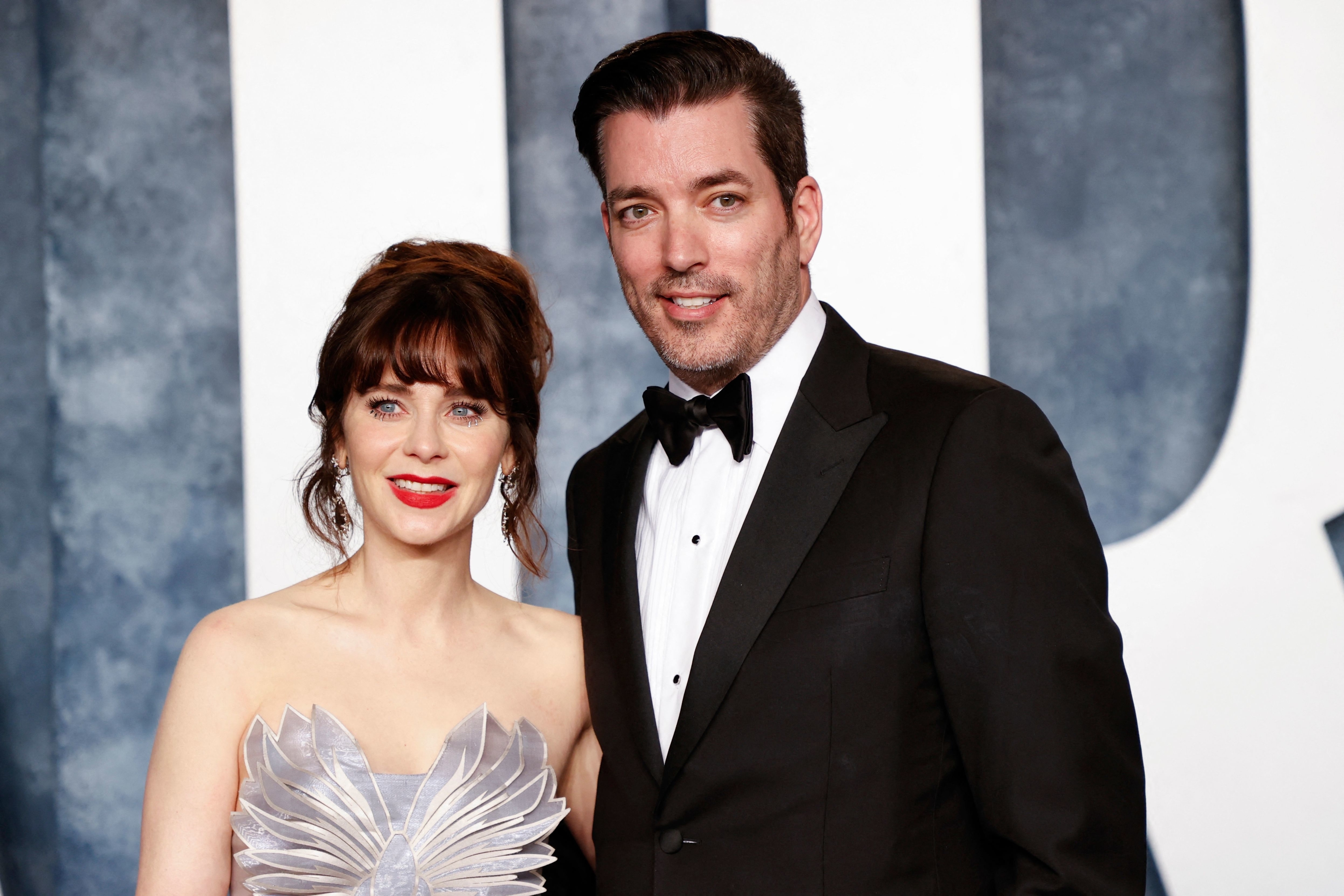 Closeup of Zooey Deschanel and Jonathan Scott at a formal event. Jonathan is in a tux and Zooey is wearing a strapless gown