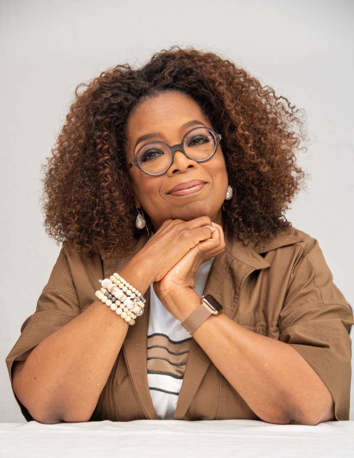 A closeup of Oprah leaning on a table and smiling