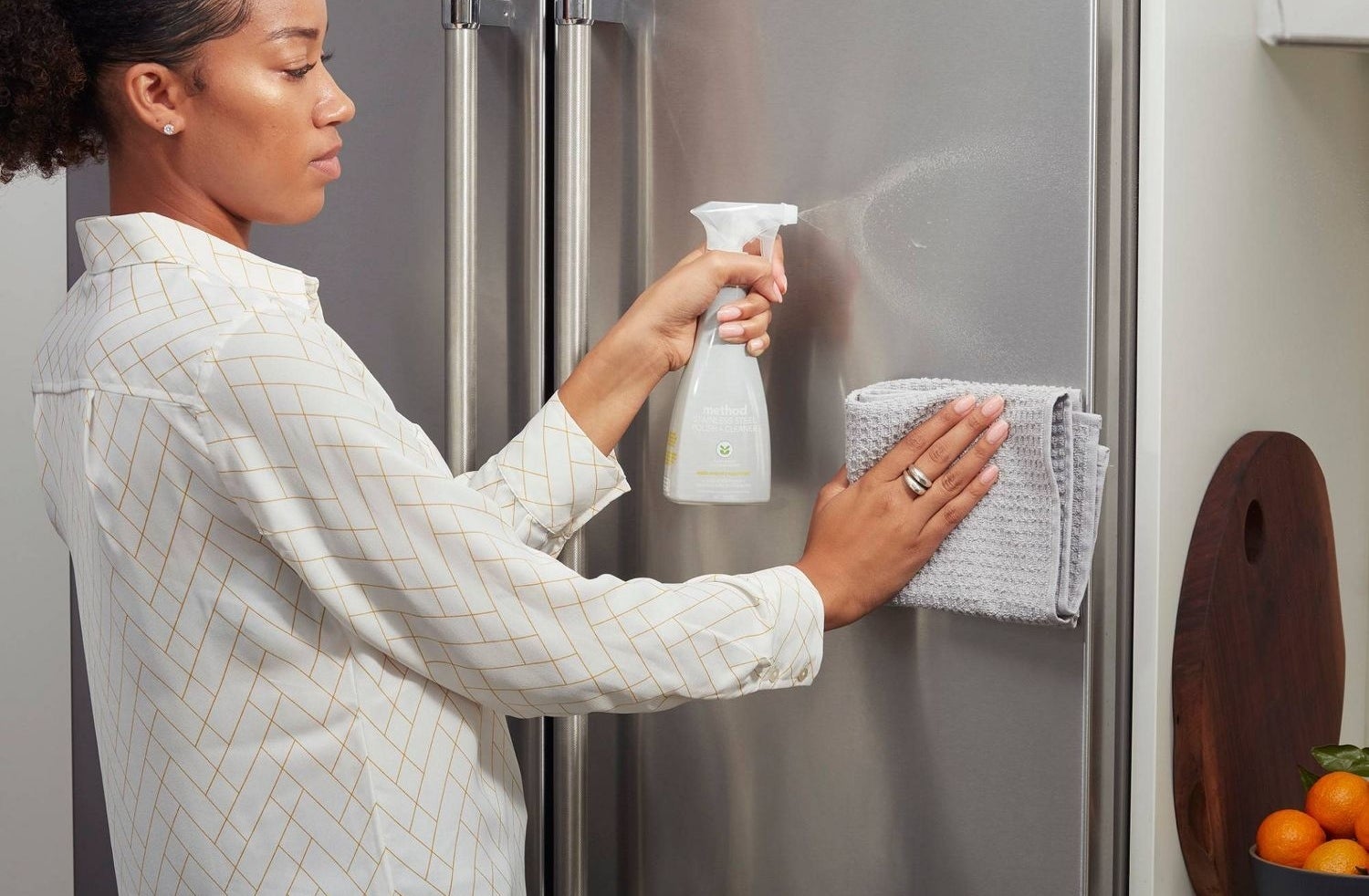 A person applying the polish to a stainless steel fridge