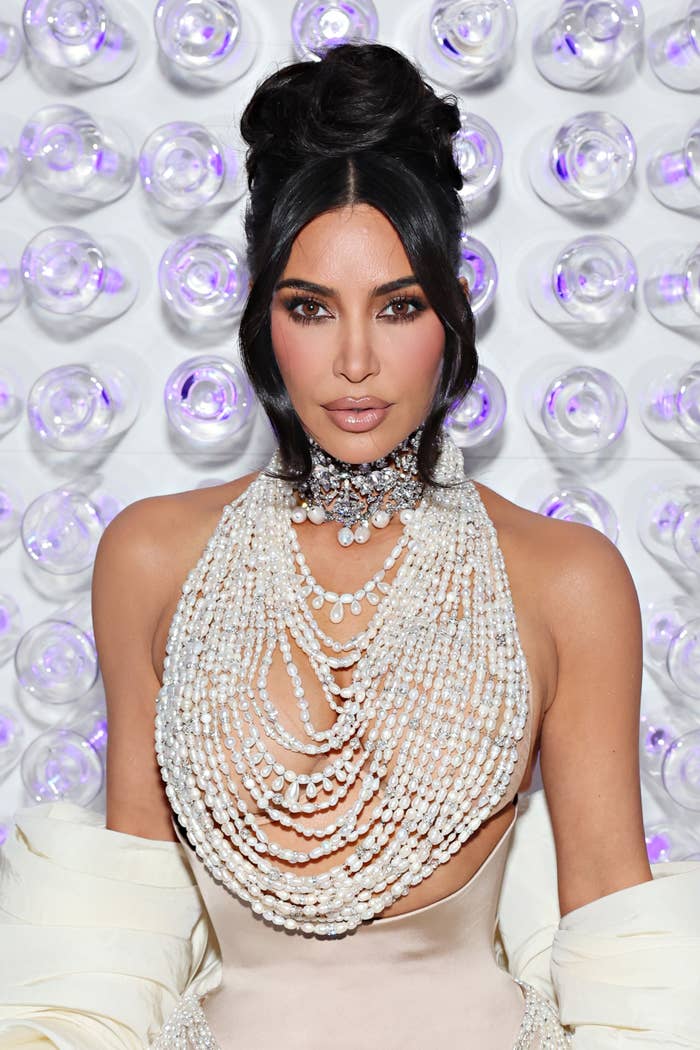 A closeup of Kim Kardashian in a pearl-string top with a cinched skirt