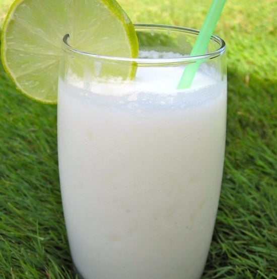 A glass of limonada de coco sits on a bed of grass