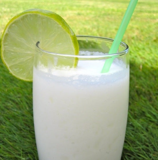 A glass of limonada de coco sits on a bed of grass