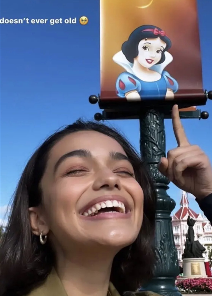 rachel at disneyland smiling widely and pointing up to a snow white photo