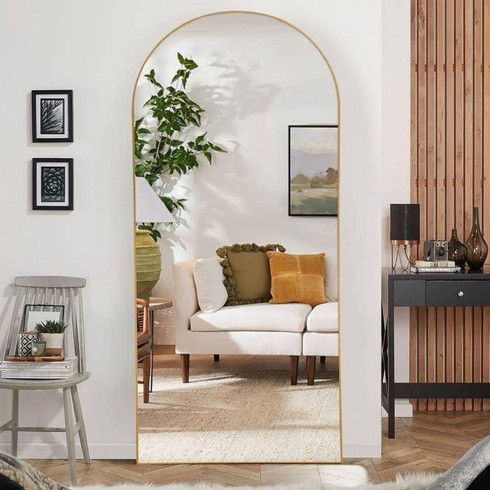 gold-tone arched floor-length mirror next to wall