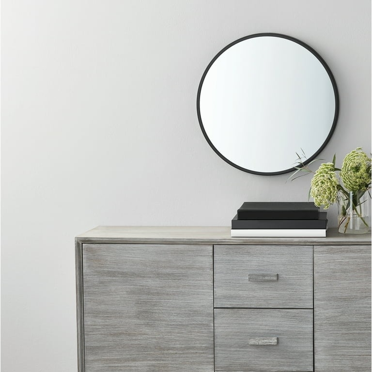 round black mirror above a grey dresser