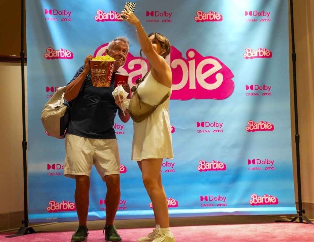 People pose in front of a Barbie themed setting at a cinema hall in New York