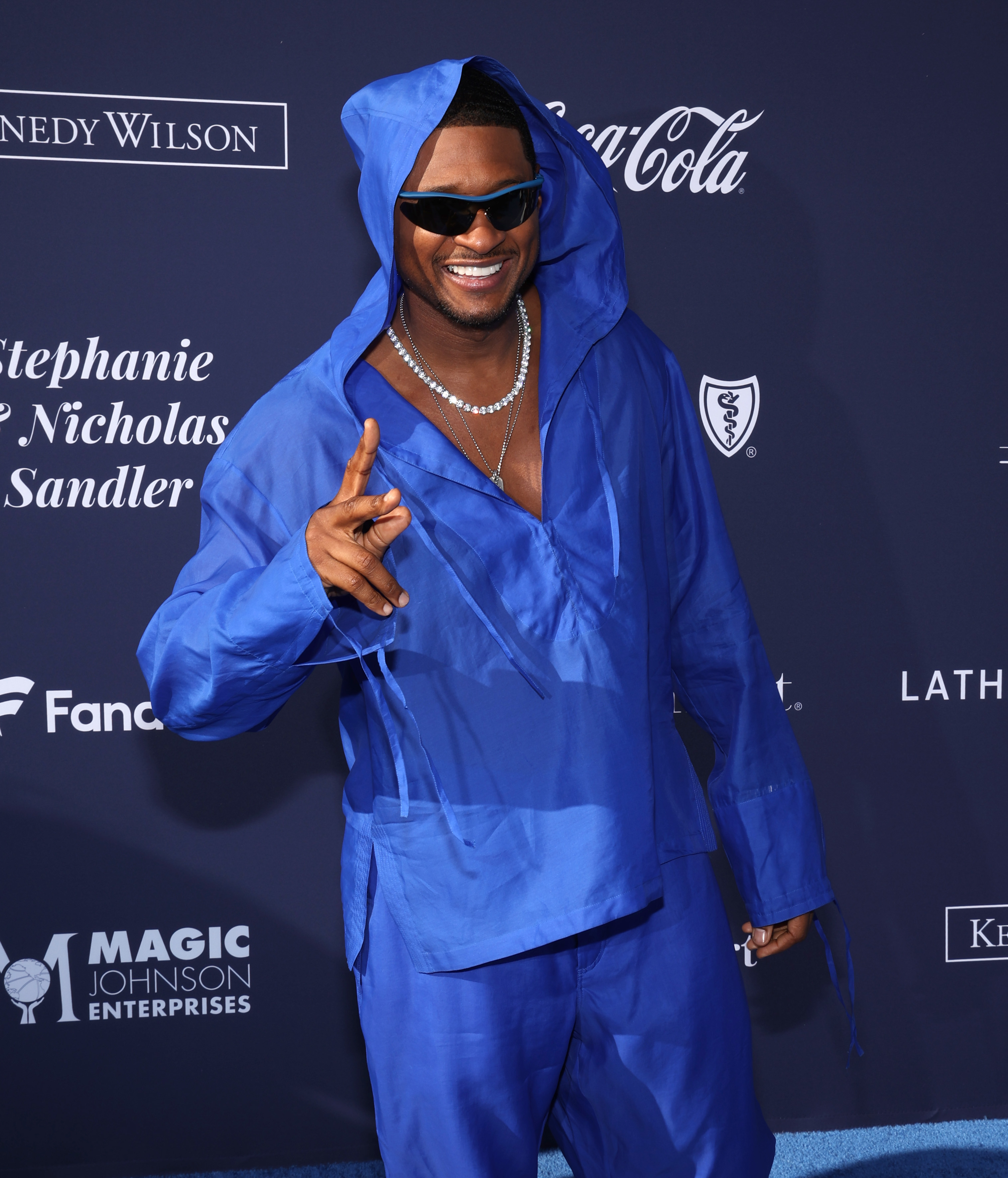 Usher flashes a peace sign at an event