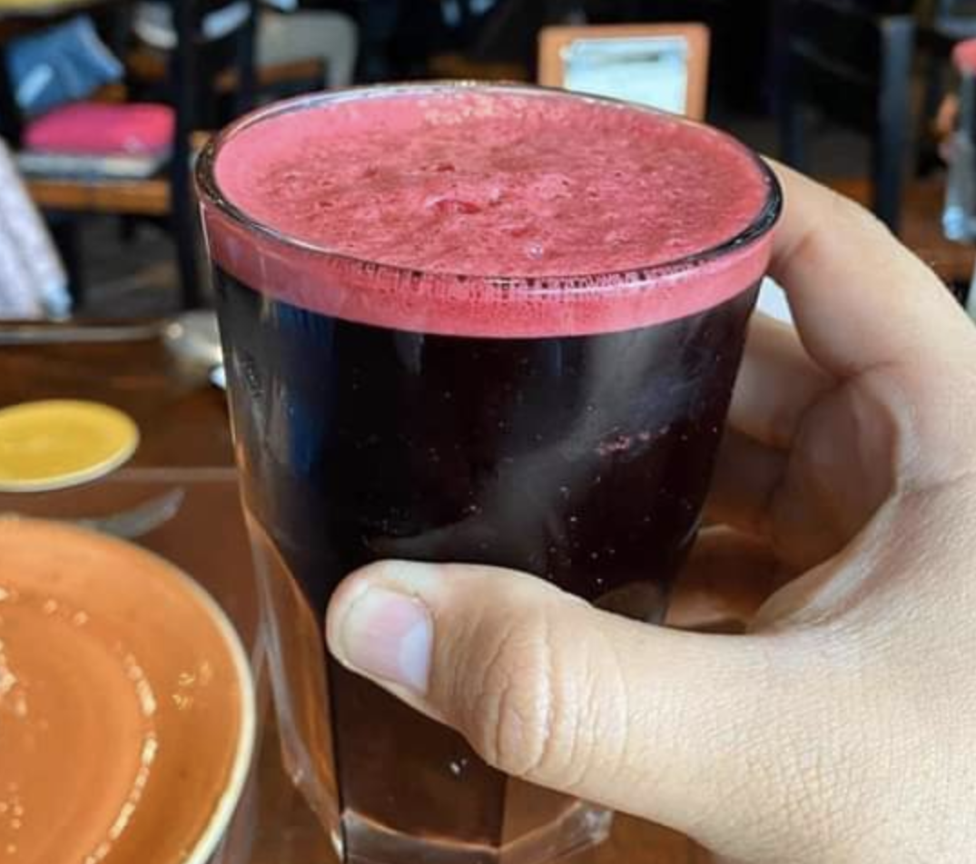 The photographer is holding up a glass of chicha morada