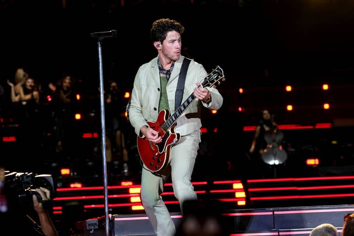 Nick Jonas playing guitar onstage