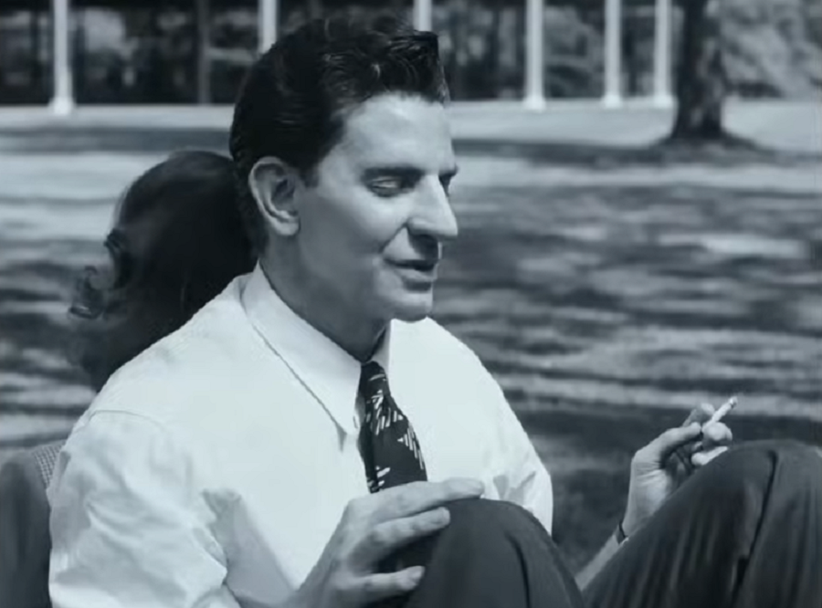 Bradley as Leonard Bernstein sitting back-to-back with a woman and holding a cigarette