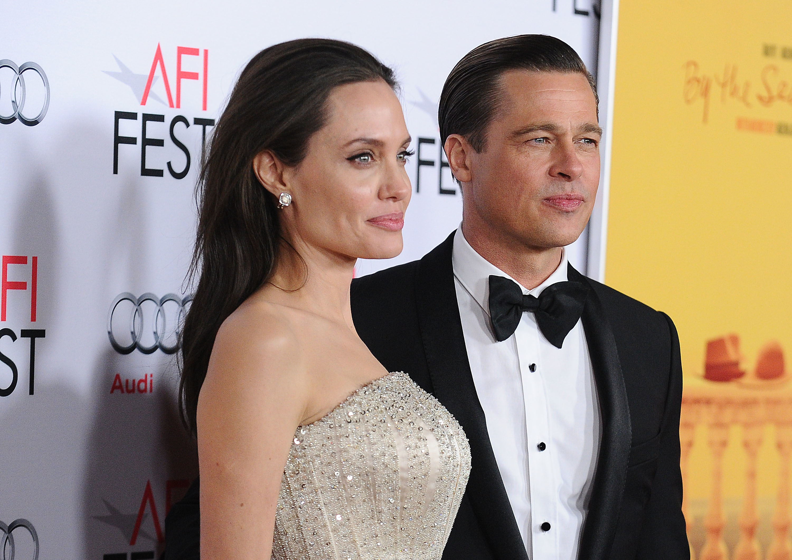 Angelina and Brad stand on the red carpet for photographers at a media event