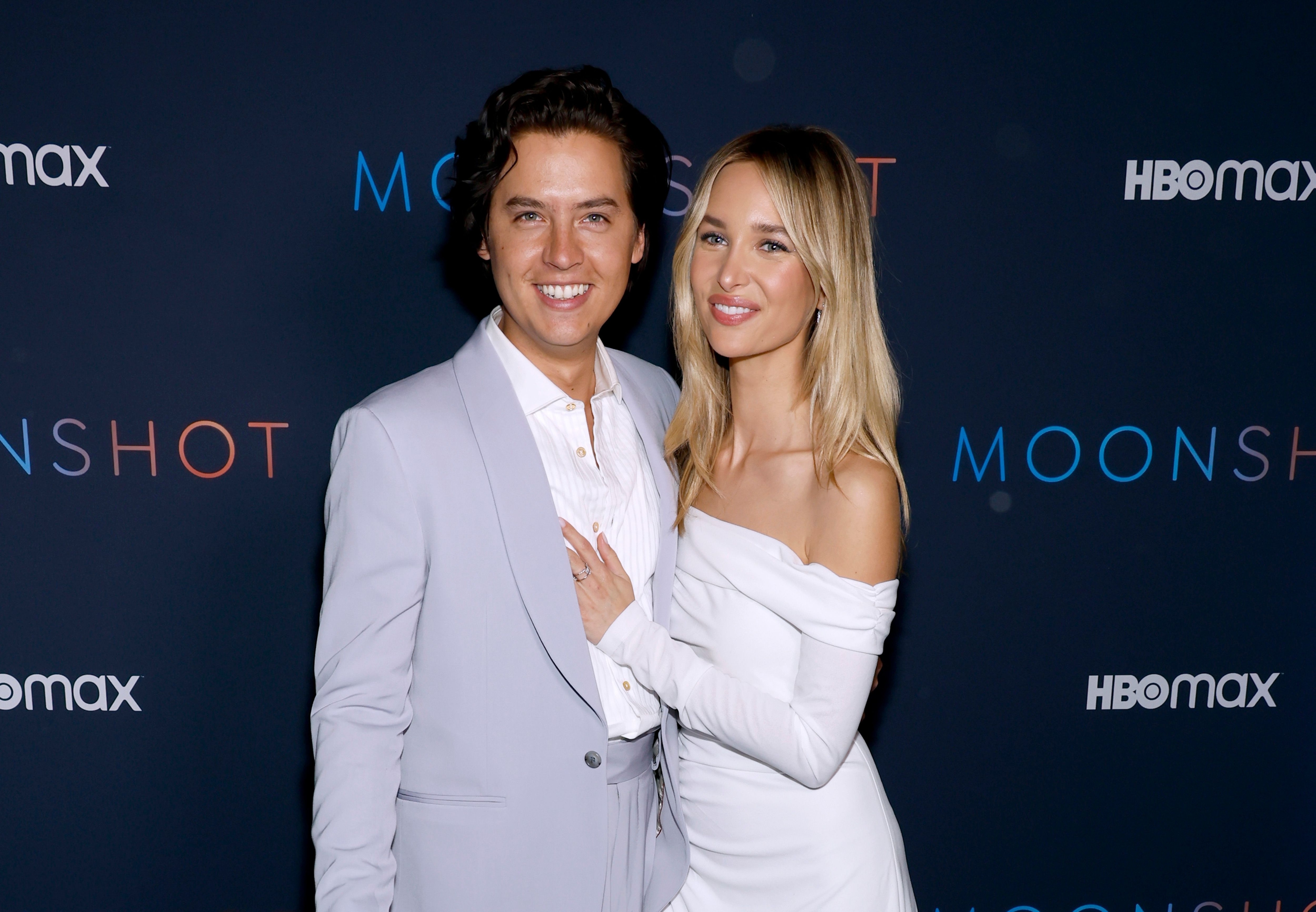 Cole Sprouse and Ari Fournier smiling for photographers at a media event