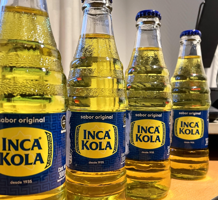 Bottles of Inca Kola are lined up on a table