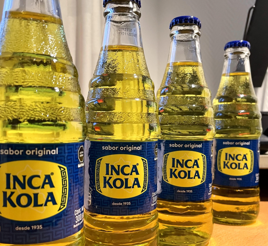 Bottles of Inca Kola are lined up on a table