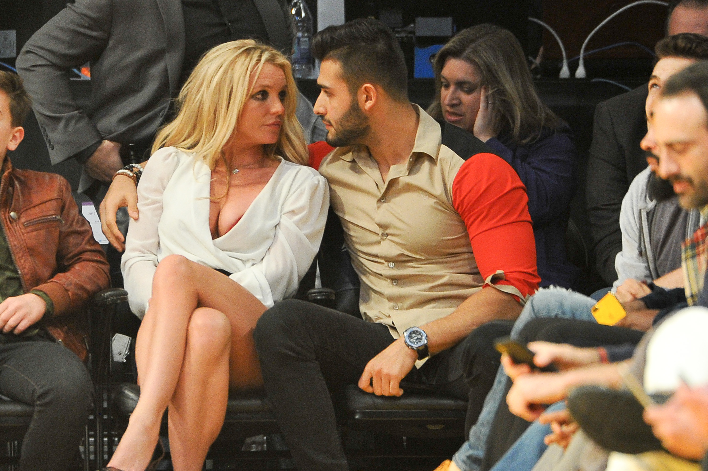 The former couple looking at each other as they sit courtside at a game