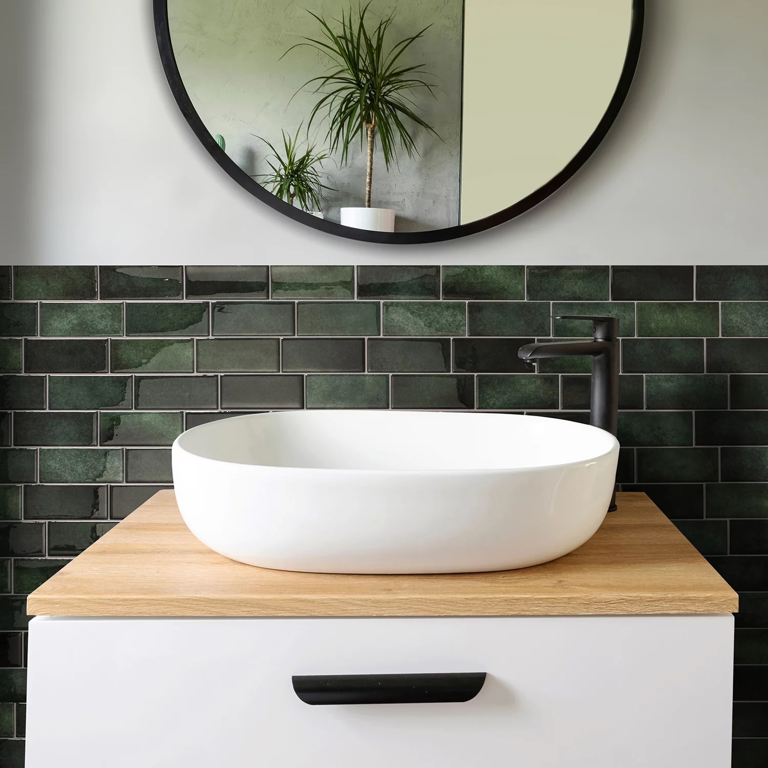 Green backsplash behind a modern bathroom vanity with a round black mirror above it