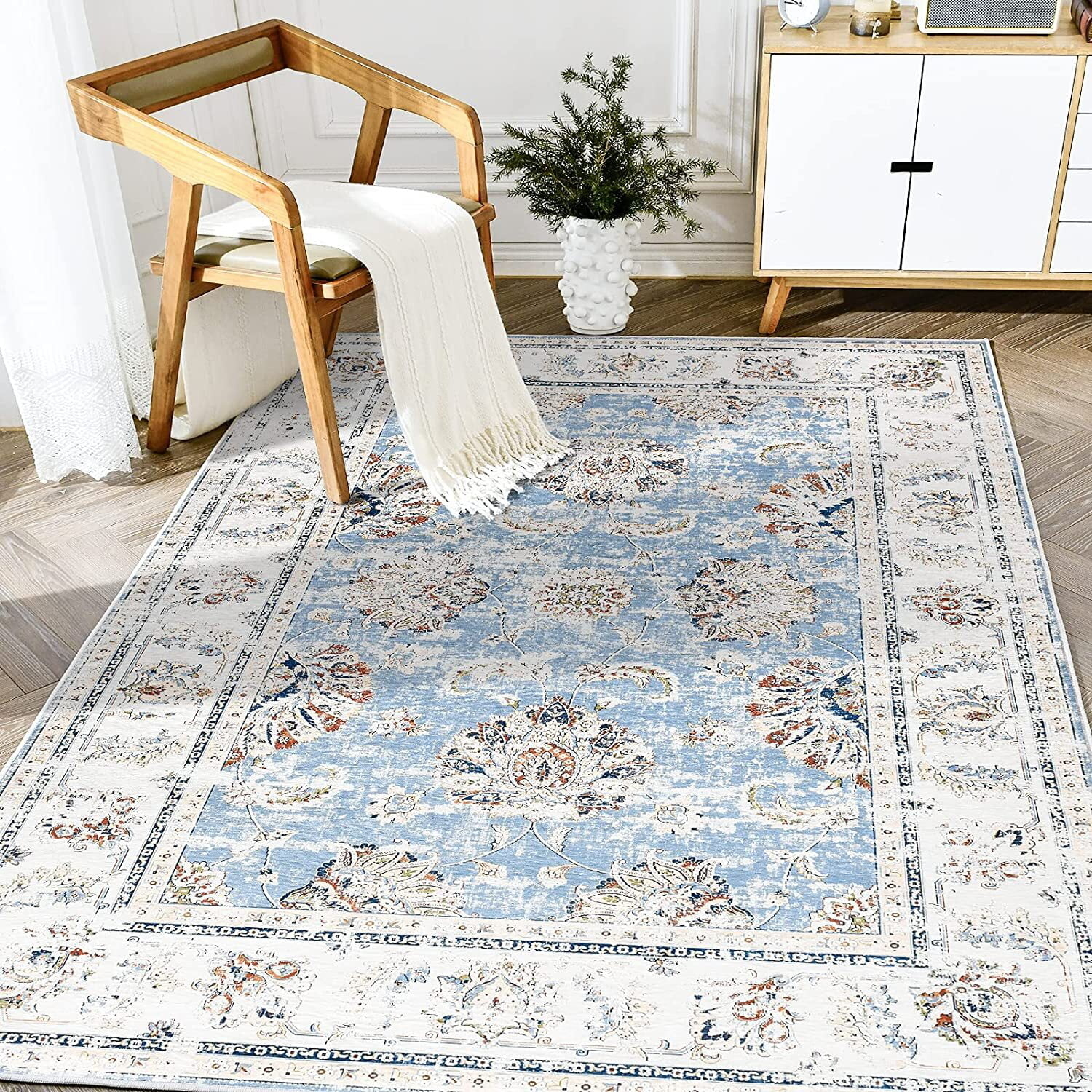 Faded area rug with blue and neutral colors in a living room with a chair on it