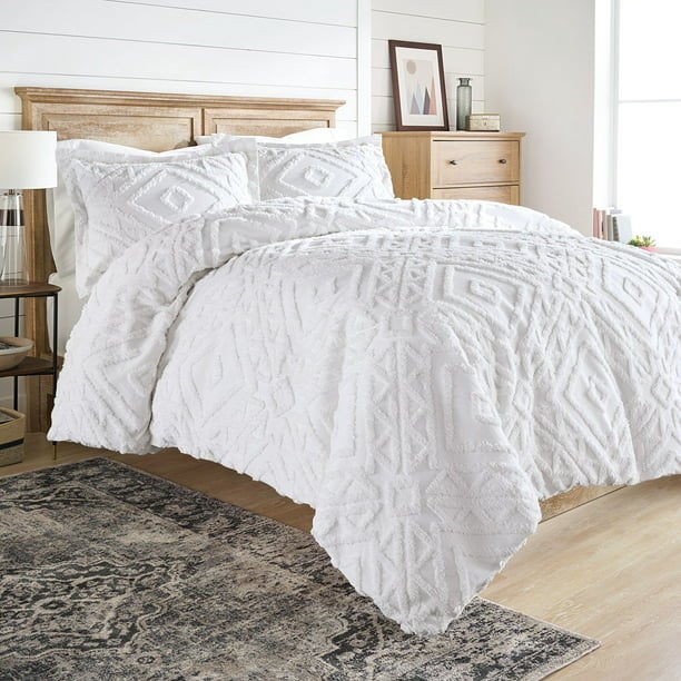 White chenille comforter and pillows on a wooden bed in a bedroom