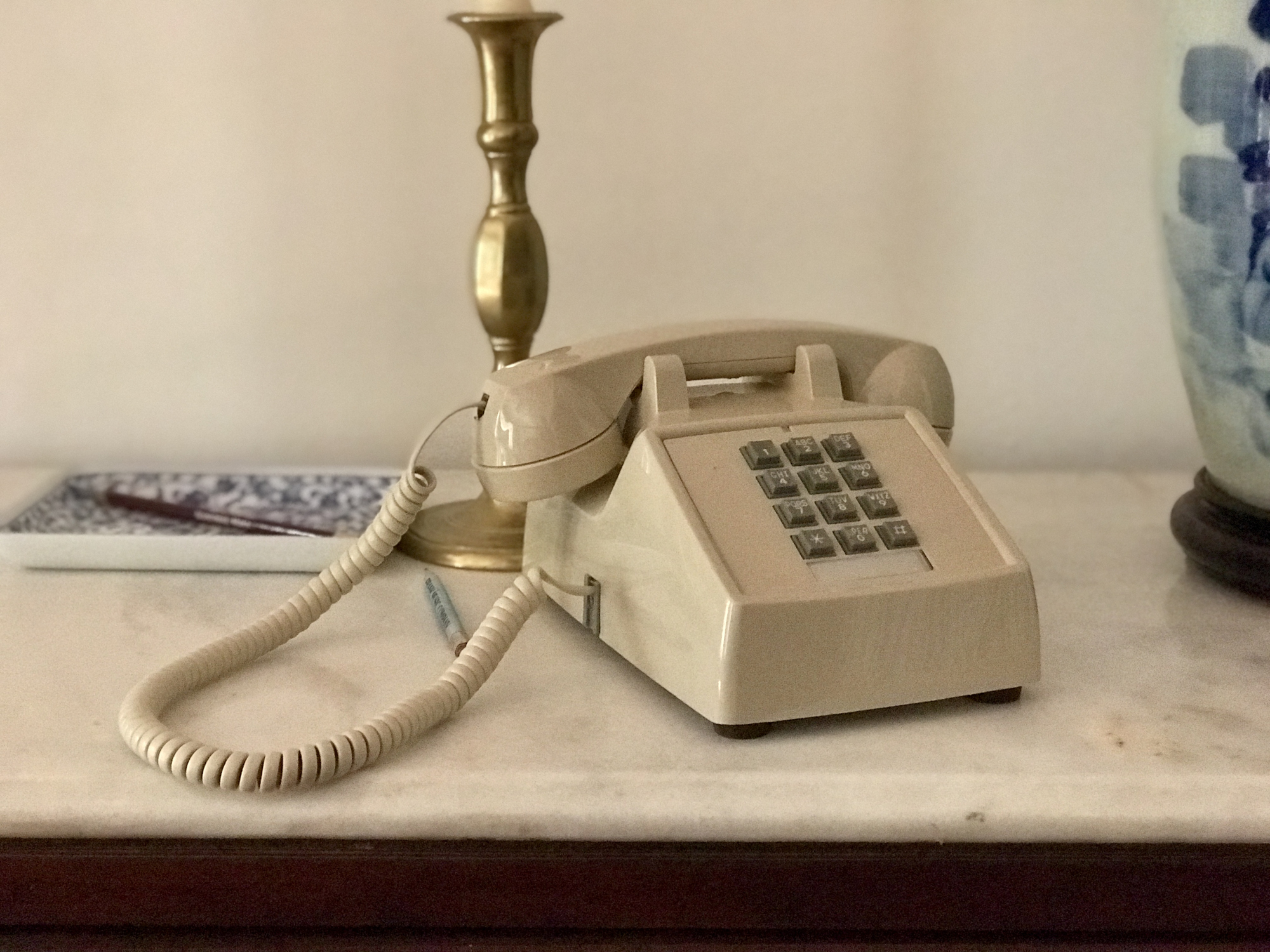 An old-school corded telephone is sitting on a nightstand