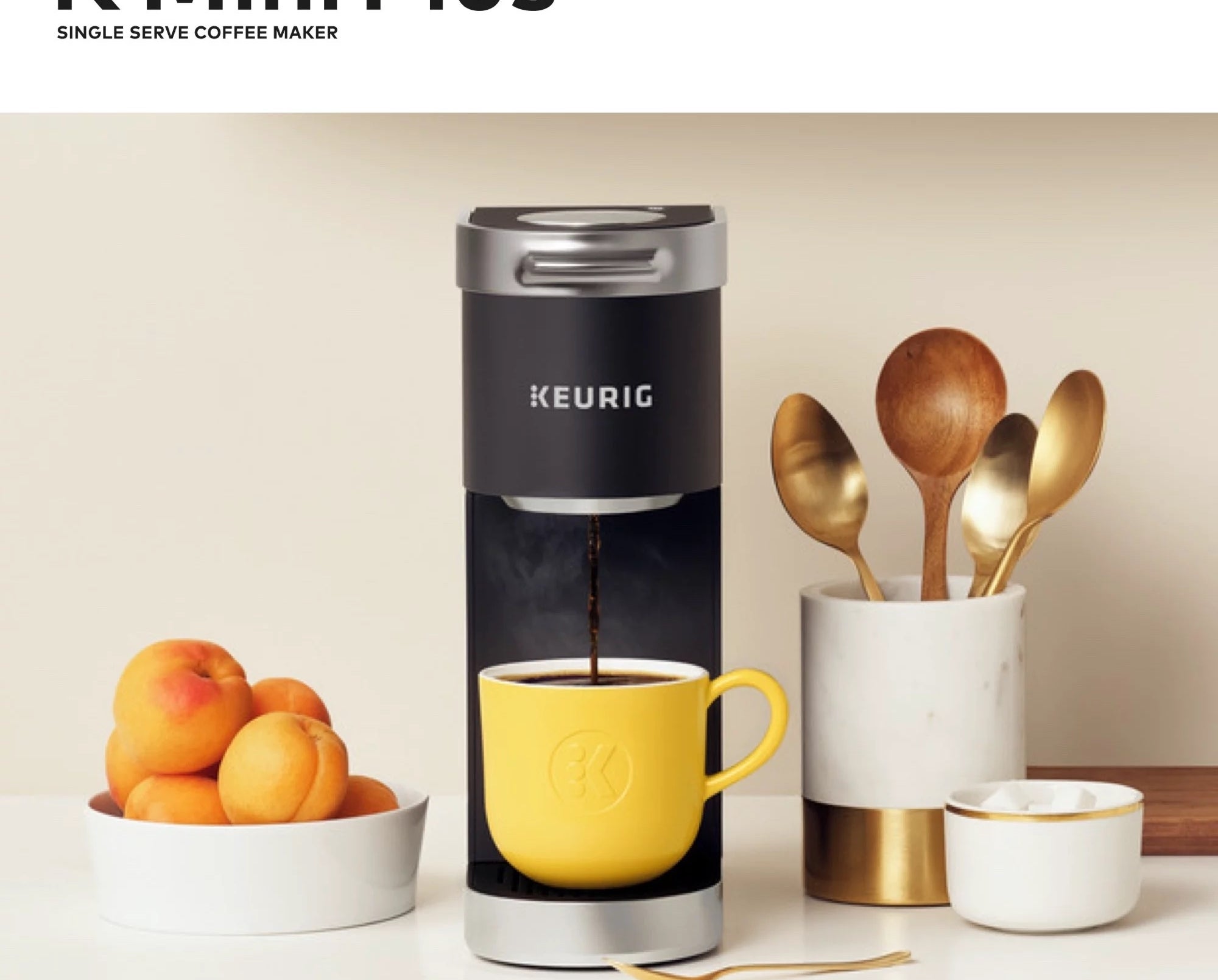 Black coffee maker with a yellow mug on a countertop with various kitchen accessories