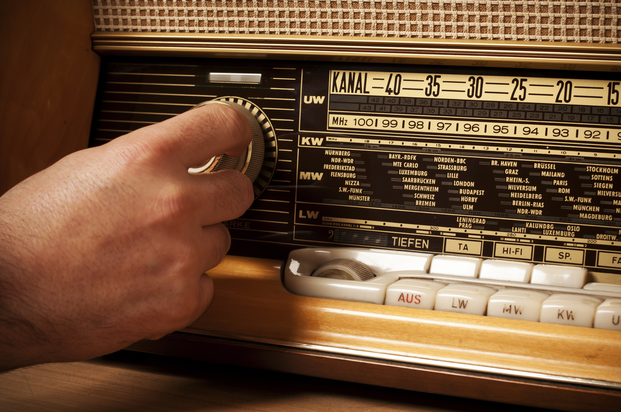 A person is finding a station on an old-school radio with a knob