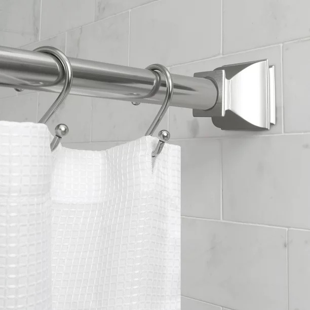 Silver rod with a white curtain hanging on it in a bathroom with marble tile