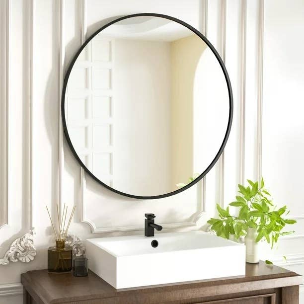 Round black mirror above a square vanity