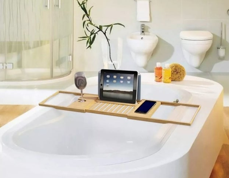 the bath caddy over the bath with a glass of wine and a tablet on it
